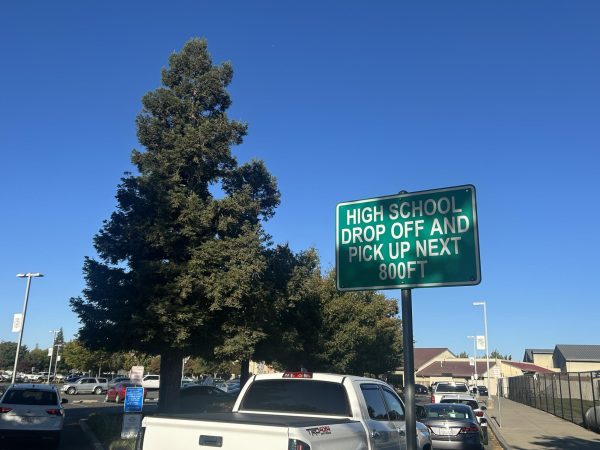 A sign directs drivers to the designated drop-off and pick-up lane 800 feet ahead at Pleasant Grove High. The traffic situation is often chaotic during drop-off and pick-up times.